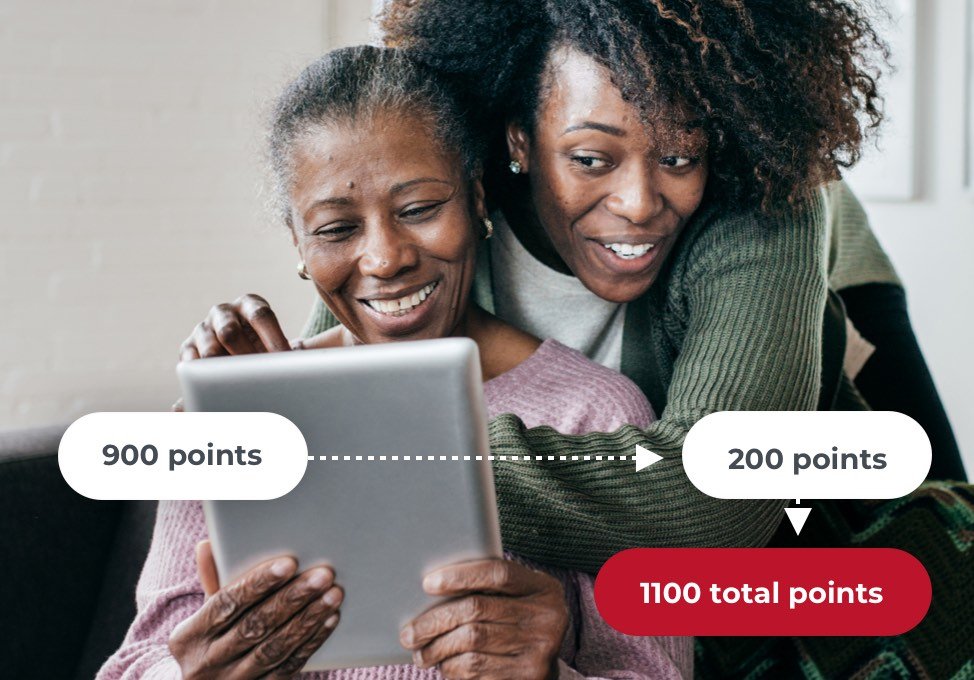 Daughter hugging older mother who is looking at a tablet.